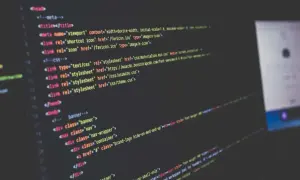 Code informatique affiché sur un écran, avec des lignes de HTML et CSS. Le logiciel Scilab est utilisé pour le développement.