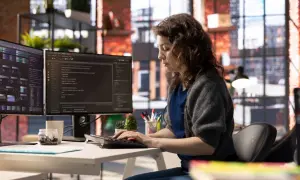 Une développeuse code sur deux écrans, explorant a quoi sert Java pour créer des applications complexes.