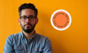 Homme confiant, lunettes, chemise en jean, devant un mur orange. Logo "SEO Bootcamp" suggérant une formation SEO diplômante.