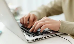 Mains sur un clavier d'ordinateur portable, utilisant des seo tools pour optimiser un site web.