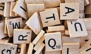 Un tas de tuiles de jeu de mots en bois, avec des lettres comme R, T, A, N, Q. Un jeu de mots amusant, comme en .lower python.