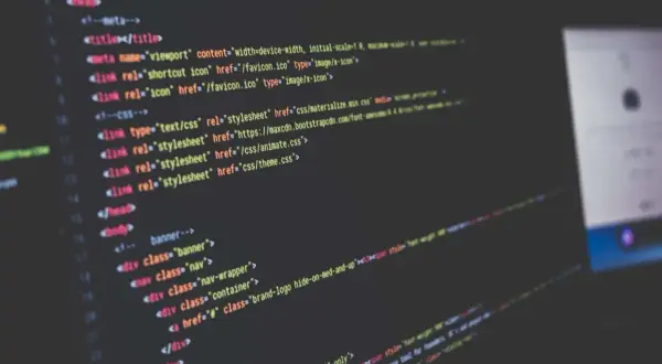 Code informatique affiché sur un écran, avec des lignes de HTML et CSS. Le logiciel Scilab est utilisé pour le développement.