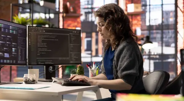 Une développeuse code sur deux écrans, explorant a quoi sert Java pour créer des applications complexes.