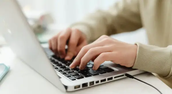 Mains sur un clavier d'ordinateur portable, utilisant des seo tools pour optimiser un site web.