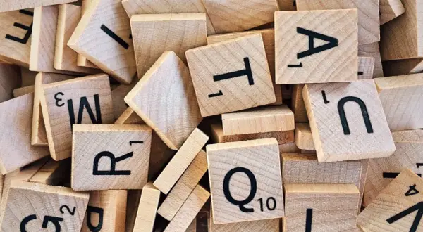 Un tas de tuiles de jeu de mots en bois, avec des lettres comme R, T, A, N, Q. Un jeu de mots amusant, comme en .lower python.
