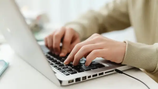 Mains sur un clavier d'ordinateur portable, utilisant des seo tools pour optimiser un site web.
