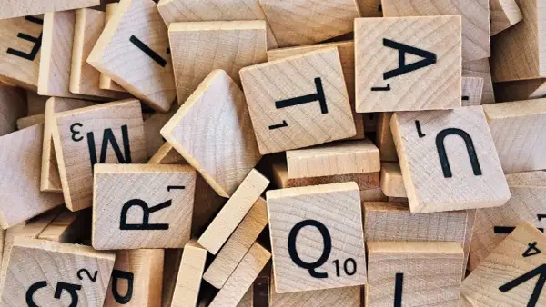 Un tas de tuiles de jeu de mots en bois, avec des lettres comme R, T, A, N, Q. Un jeu de mots amusant, comme en .lower python.